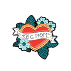 A traditional tattoo-style enamel pin featuring a red heart with a gold border, teal flowers, and teal leaves on a white background