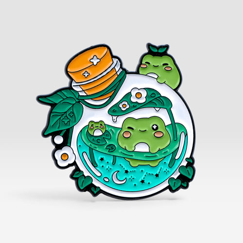 Green potion bottle enamel pin featuring small frogs, leaves, and colorful potion details