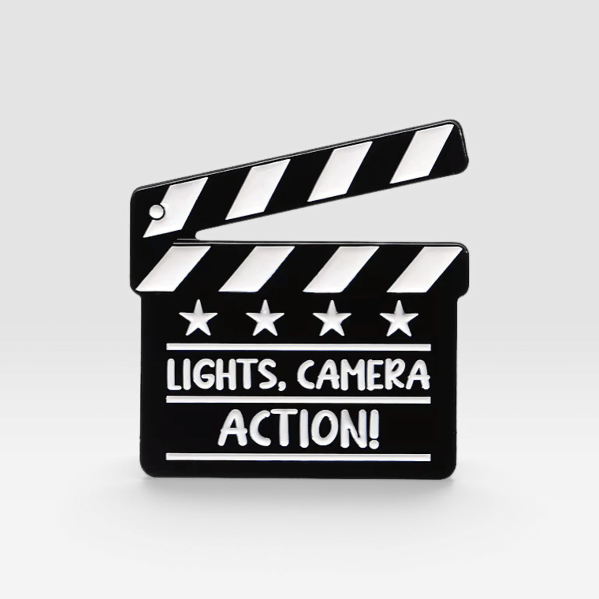 Black and white movie clapperboard enamel pin featuring the words "Lights, Camera, Action!"