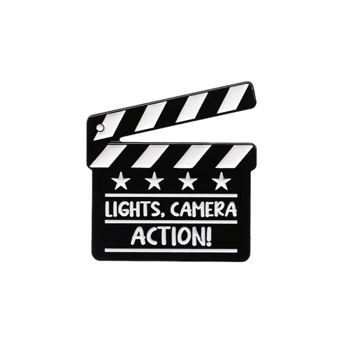 A black clapperboard pin with the words 'LIGHTS, CAMERA ACTION!' on a white background