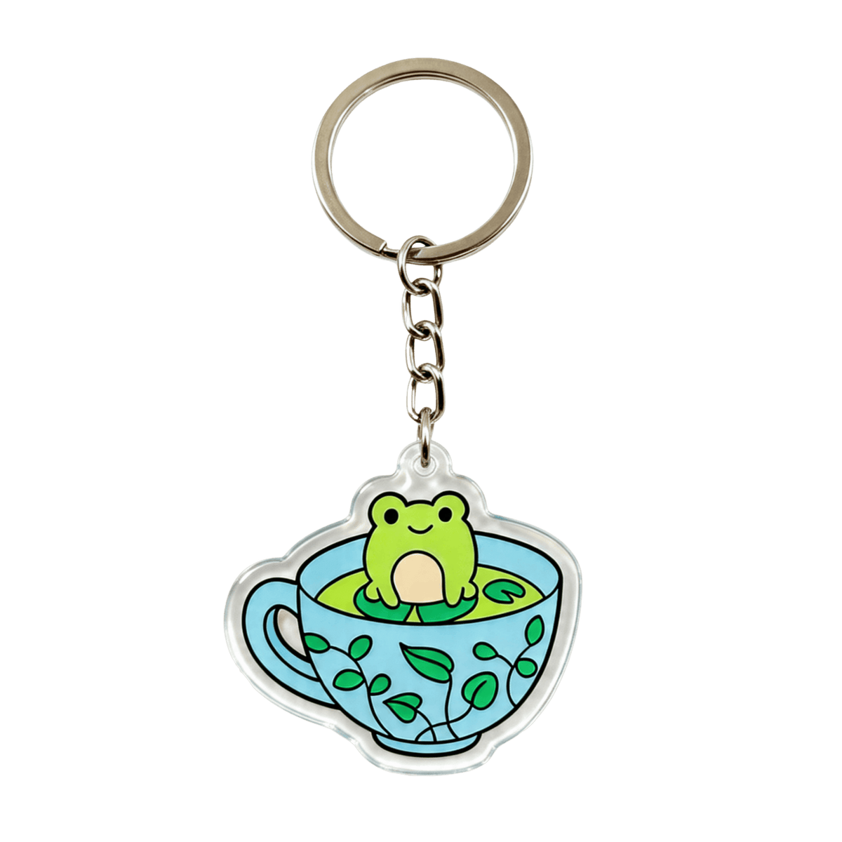 A clear acrylic keychain charm shaped like a light blue teacup with green leaf patterns, featuring a cute green frog sitting in the center, attached to a chain and a split key ring on a white background